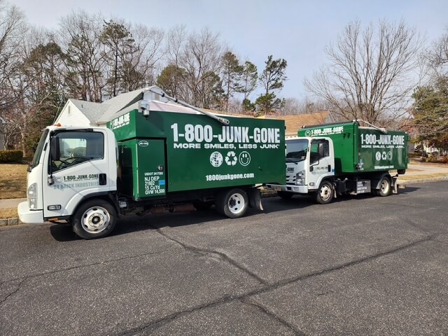 Two green 1-800-JUNK-GONE trucks parked on a residential street, ready for junk removal services.