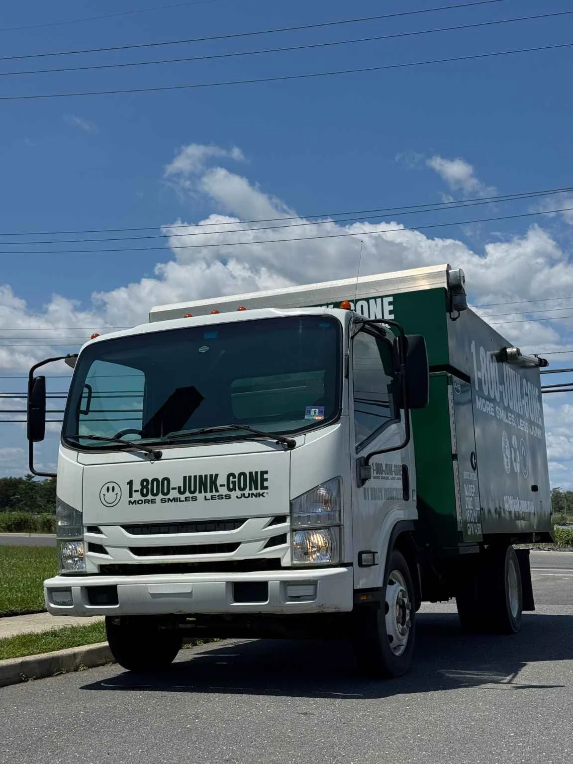 Front view of a 1-800-JUNK-GONE junk removal truck parked outdoors under a sunny blue sky