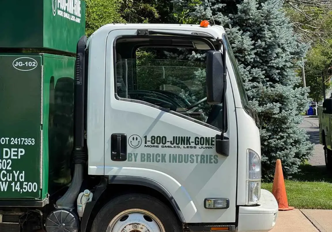 Side profile view of the white driver cab of a 1-800-JUNK-GONE removal truck