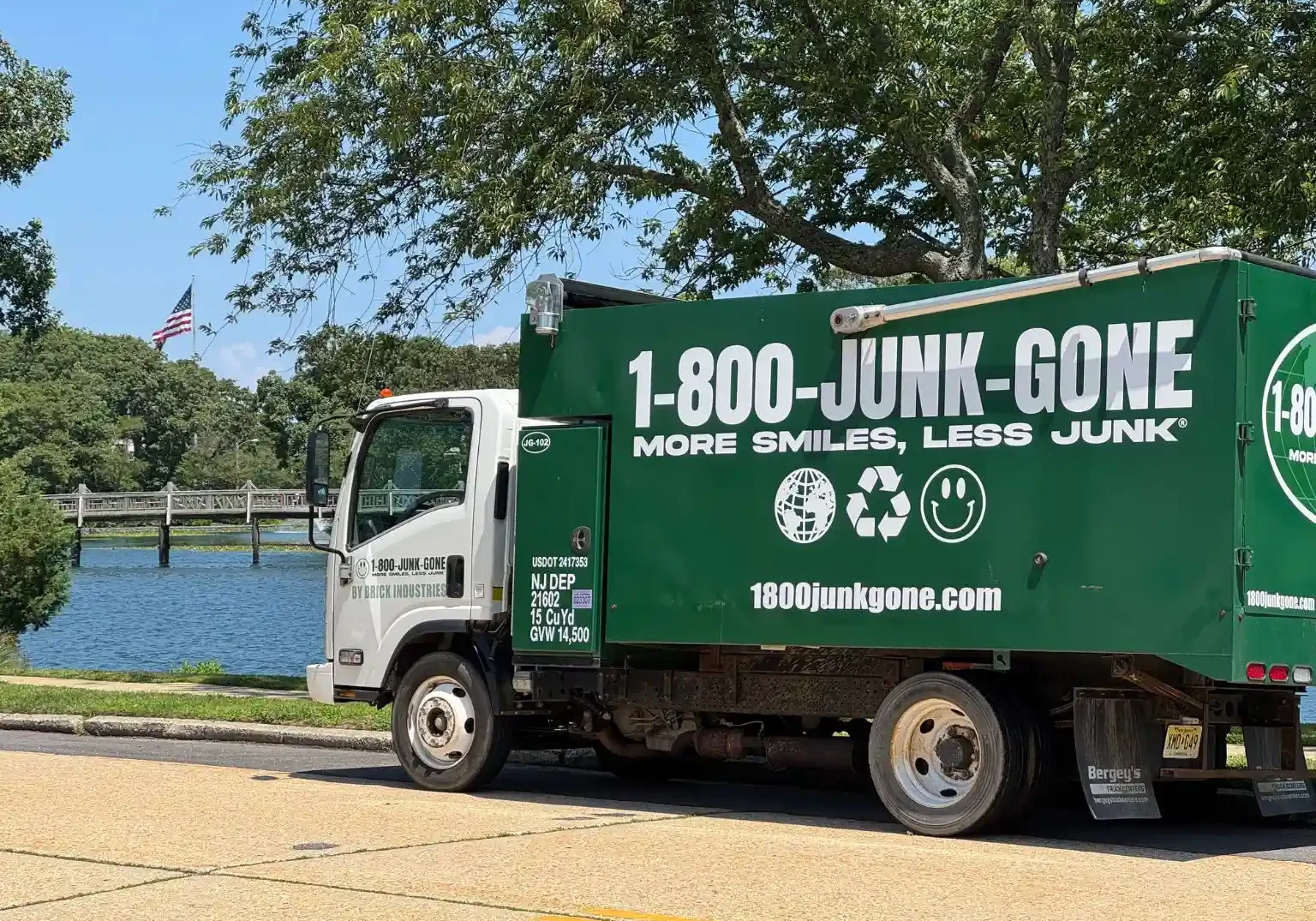 Close side profile of a 1-800-JUNK-GONE truck parked along the curb near water