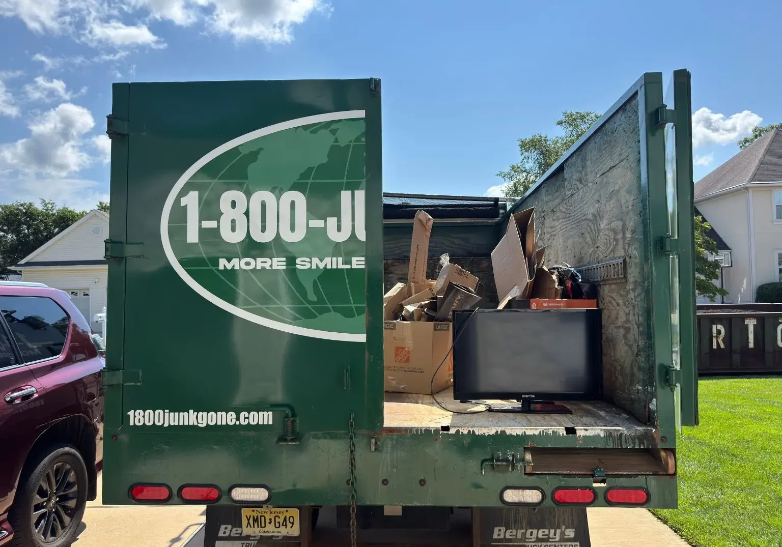 Rear view of an open junk removal truck loaded with cardboard boxes and electronic waste