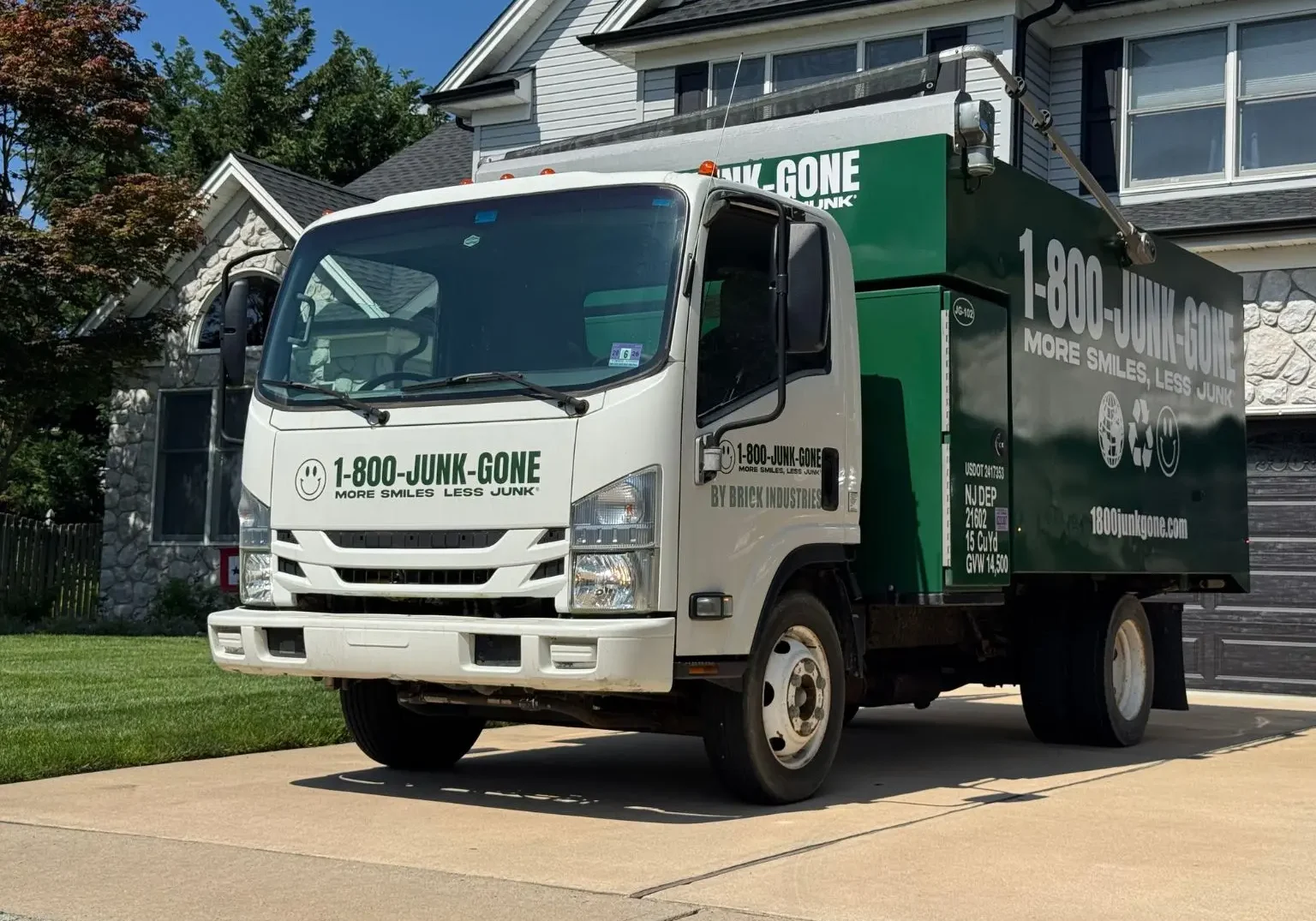 Three-quarter front angle of a 1-800-JUNK-GONE truck parked in a home driveway
